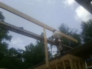 Carpenter setting a ridge beam over a new addition frame — Ice Dam Removal by Roofing Brothers in Summit Point