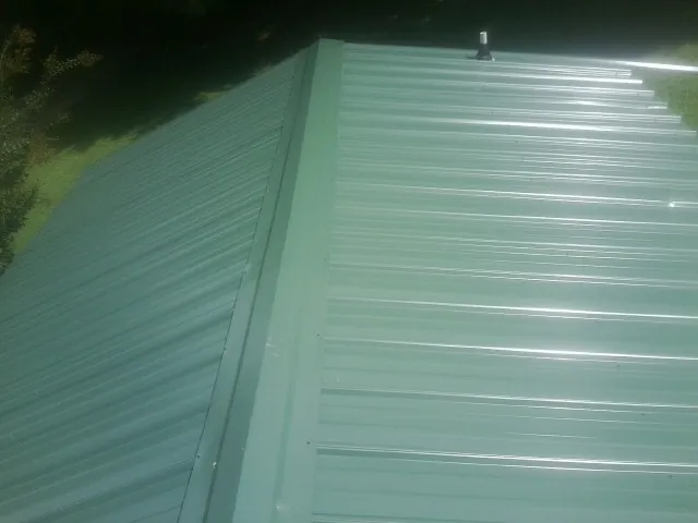 New green metal panels meeting at the ridge of a roof — Flat Roof Repair work by our crew in Summit Point
