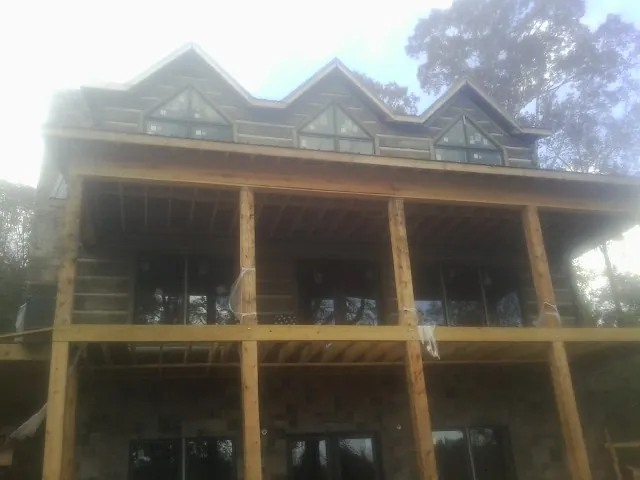Dormers and porch framing on a large log home under construction — Roof Coating work by our crew in Summit Point