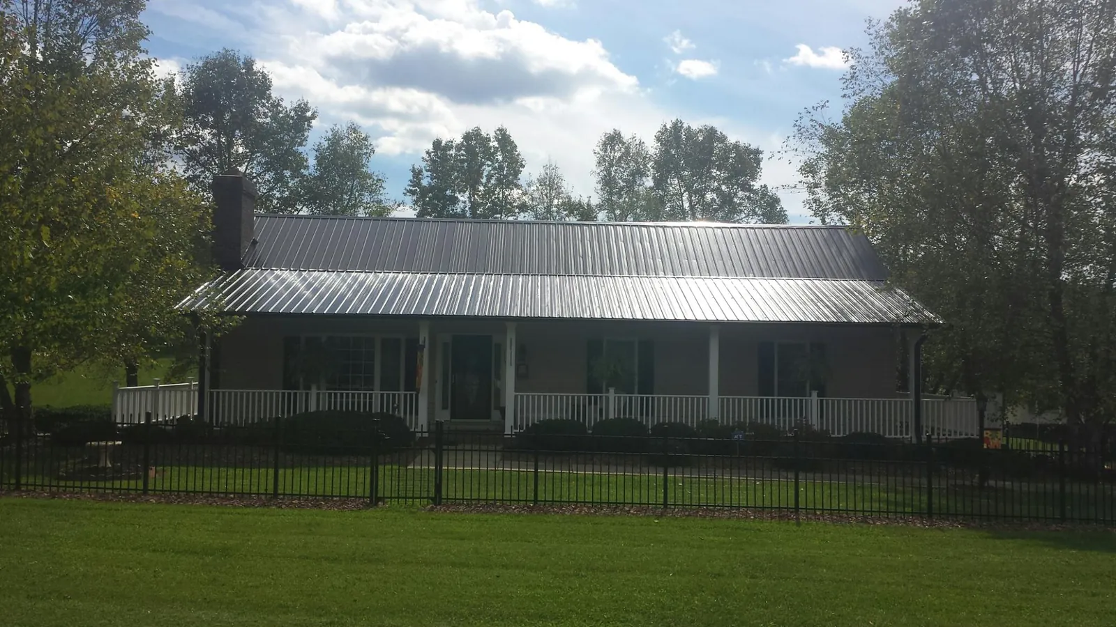Gray metal roof on a brick ranch with a full width front porch — Gutter Guard Installation work by our crew in Summit Point