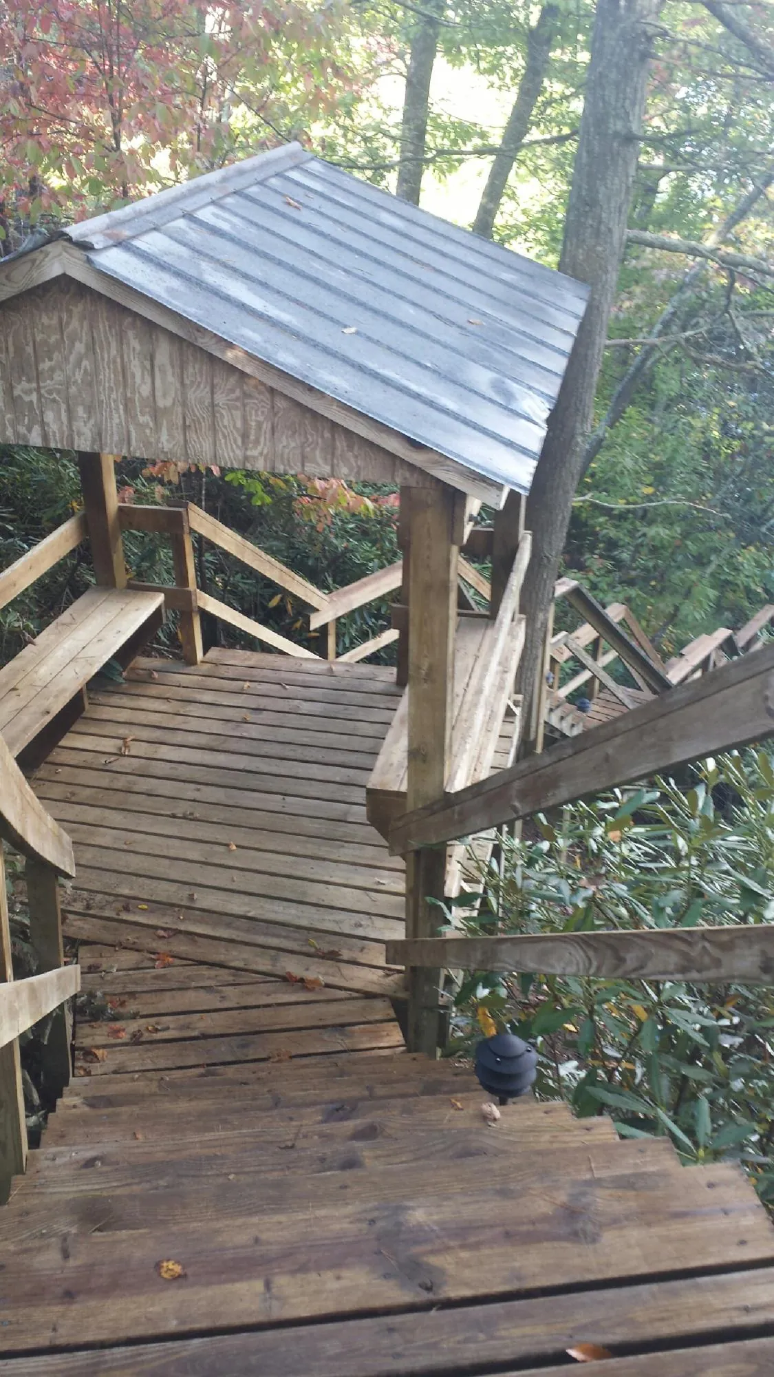 Metal roofed shelter over wooden steps on a wooded walkway — Skylight Repair & Installation work by our crew in Summit Point