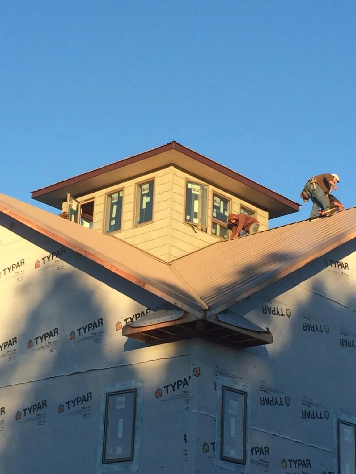 Roofers working around a rooftop cupola on a new metal roof at sunset — Roof Waterproofing in Summit Point by Roofing Brothers